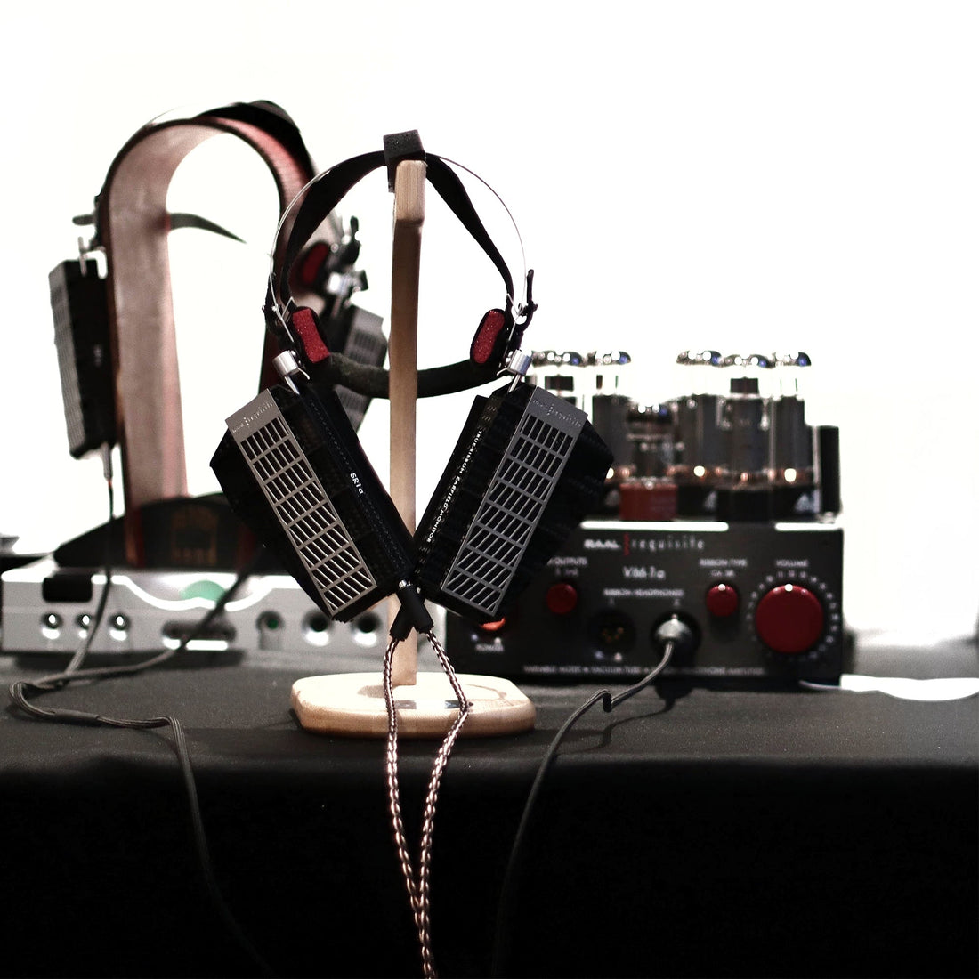 RAAL SR1a ribbon headphone sits on table in front of VM-1a tube amp and Chord TT2 DAC in silver
