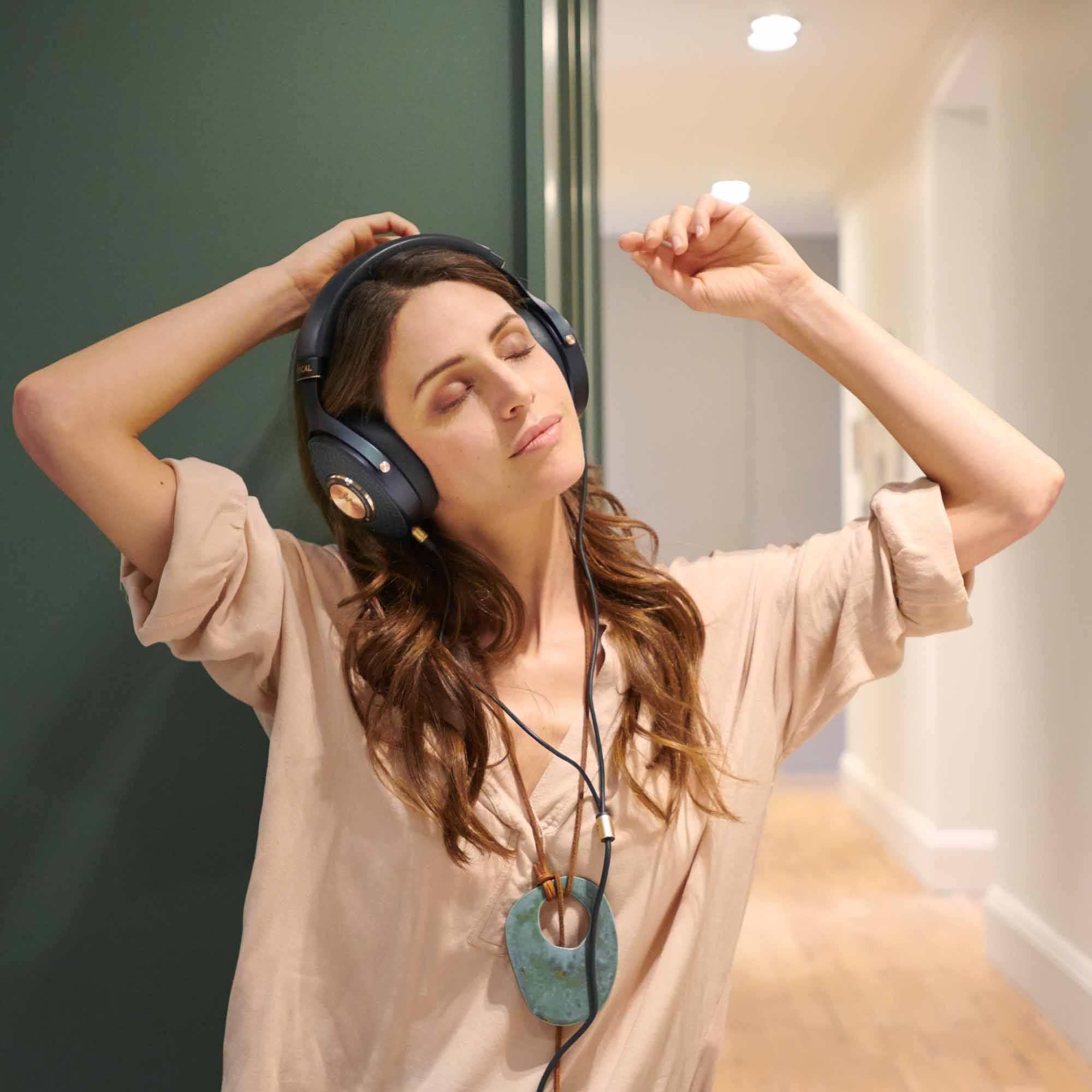 Woman in hallway listening to blue and gold Focal Celestee headphones