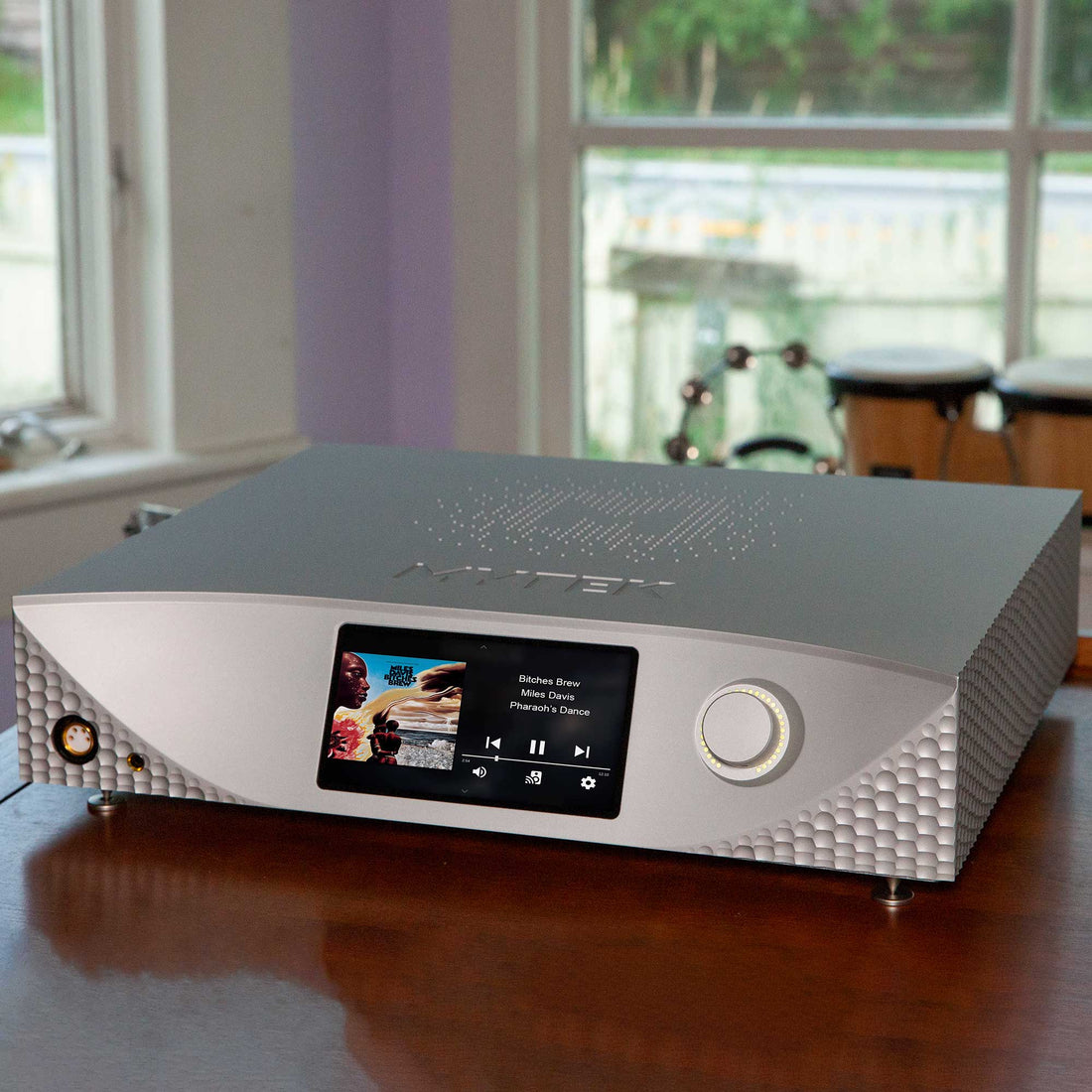 A silver Mytek Empire music streamer with touchscreen display on a wood table