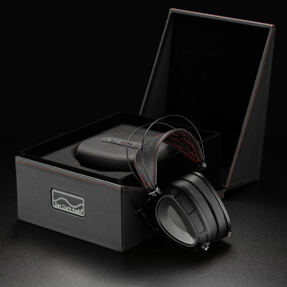 Dan Clark Stealth flagship closed-back headphone leaning against open presentation box with carrying case inside
