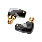 Close-up of Campfire Axion IEMs with black and gold finish showcasing detailed nozzle design on white background