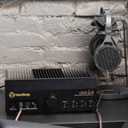 Abyss AB-1266 Phi TC headphones hanging on a stand connected to a black HeadAmp cfa3 ss-zf amplifier against a textured wall