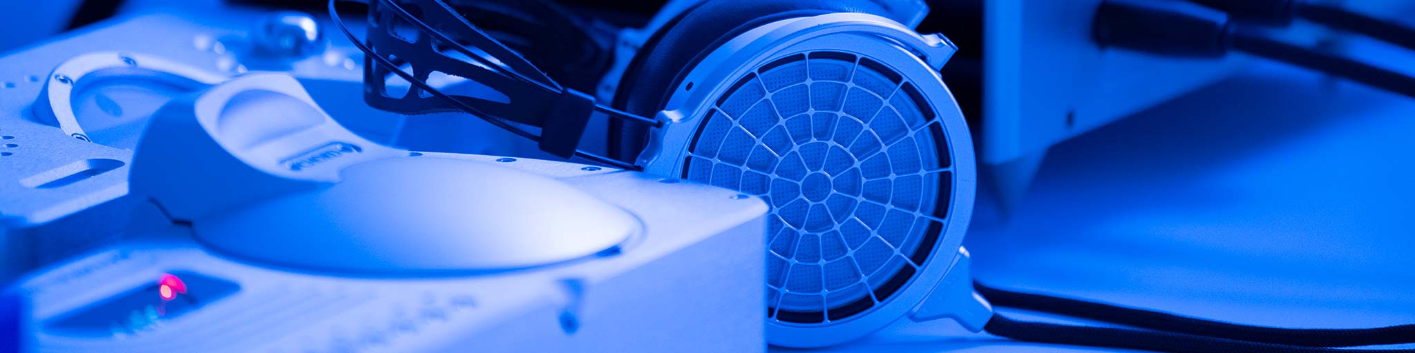 Close up of Dan Clark Voce headphones and Chord CD player, on a table bathed in blue light