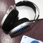 HIFIMAN Ananda | Nano open back headphones with silver frame and black ear pads resting on textured surface