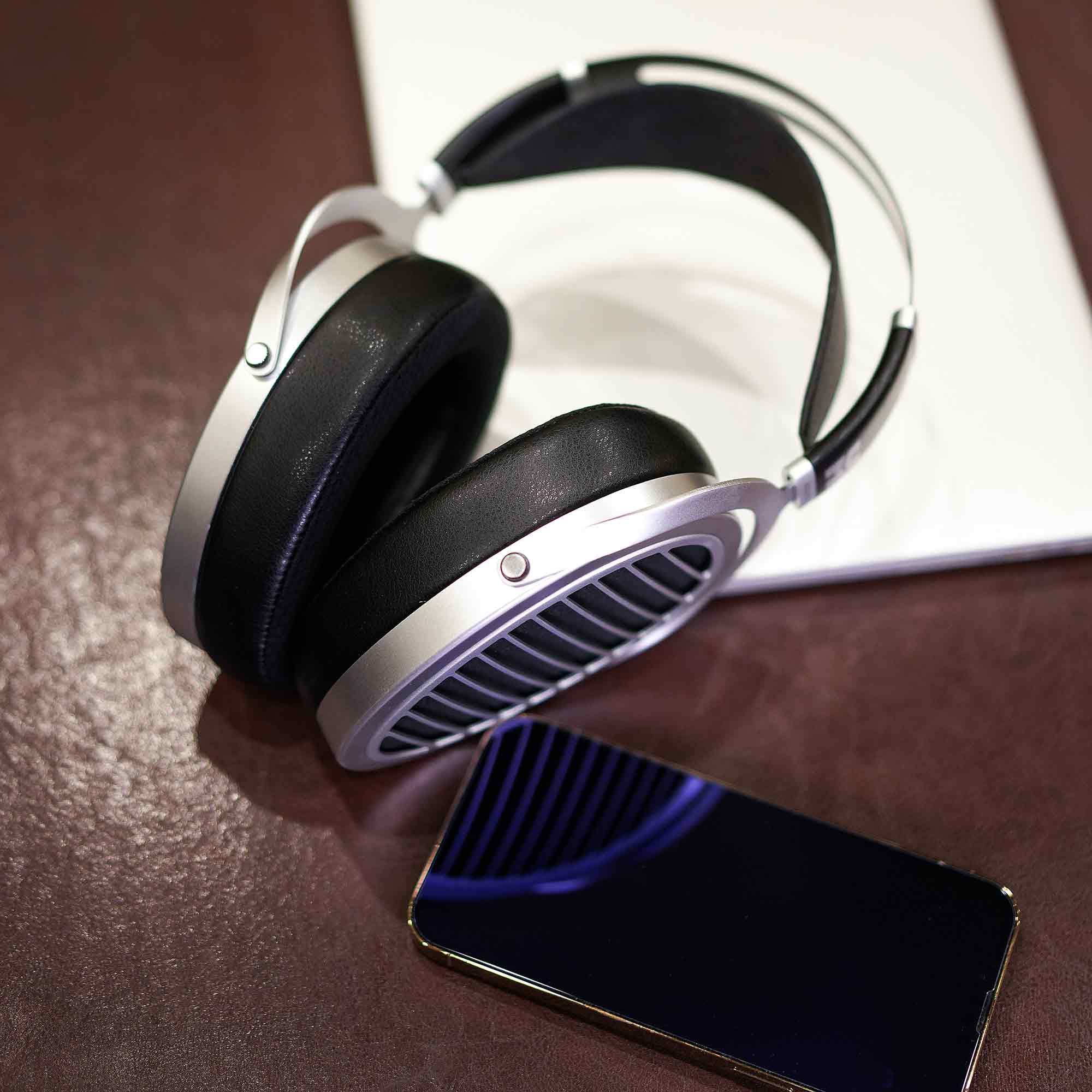 HIFIMAN Ananda | Nano open-back headphones resting on leather surface next to a smartphone with reflective screen