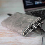 iFi Audio Hip Case for Hip-DAC Series in gray suede protecting a compact DAC with volume knob and headphone jack connected to a laptop