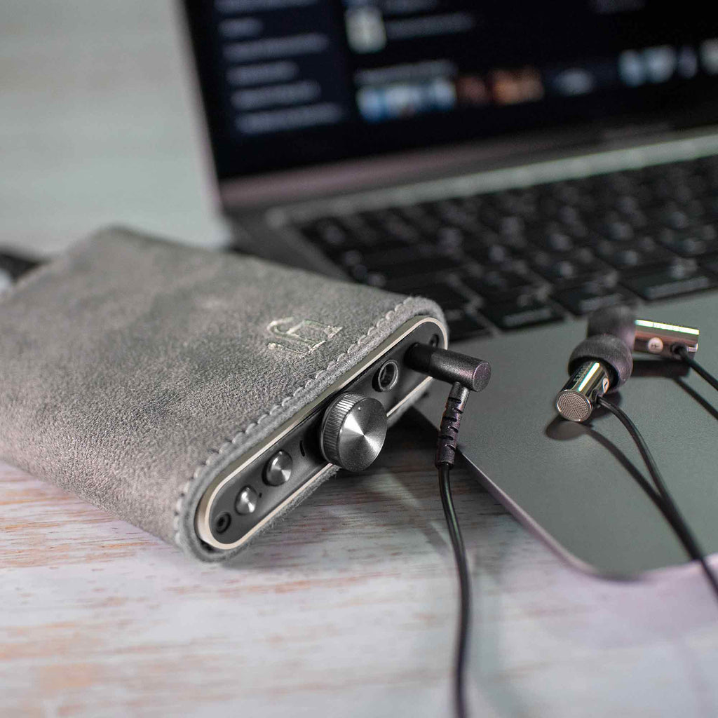 iFi Audio hip-dac3 Portable USB DAC/Amp in suede case connected to laptop with wired earphones on wooden surface