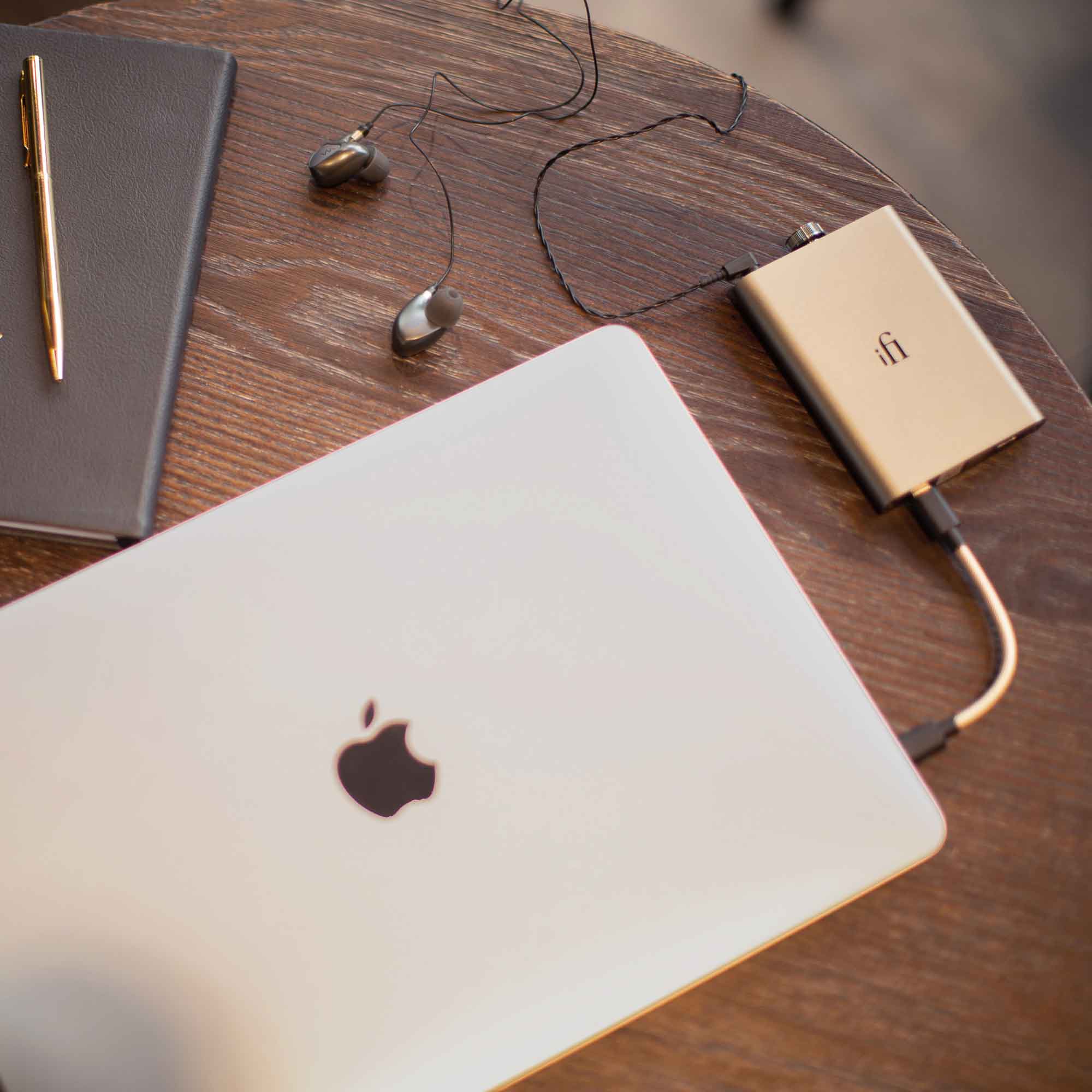 iFi Audio hip-dac3 Portable USB DAC/Amp in titanium shadow connected to a laptop with wired earphones on wooden table
