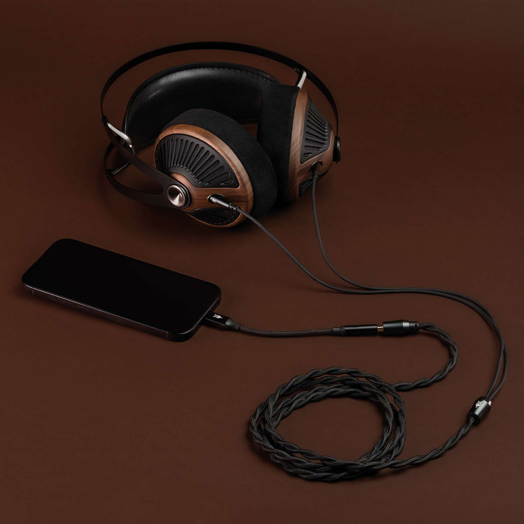 Meze 105 SILVA Dynamic Open-Back Headphones with wood ear cups connected to a smartphone on a brown surface