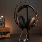 Meze Manta Headphone Stand displaying headphones with wooden ear cups and braided cable on a dark surface