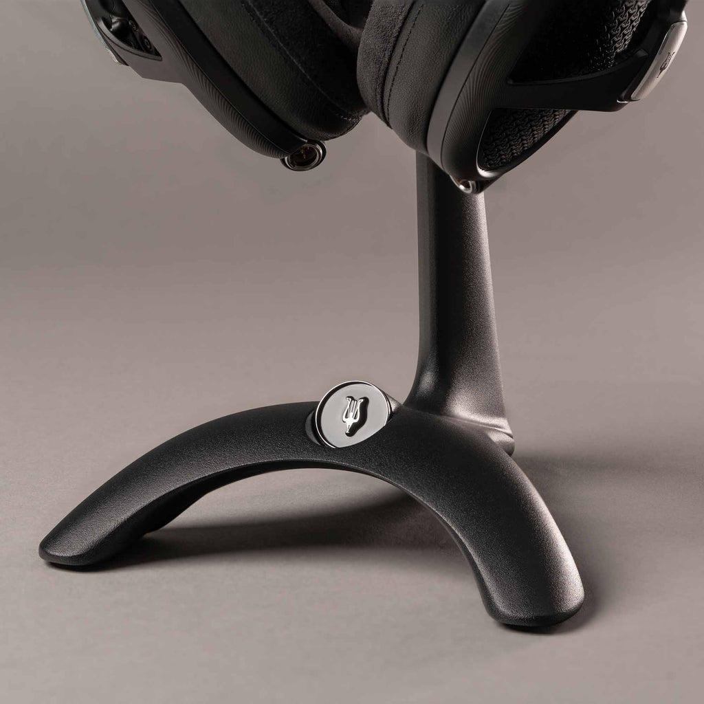 Close-up of the base of the Meze Manta Headphone Stand holding headphones with a dark matte finish and logo detail