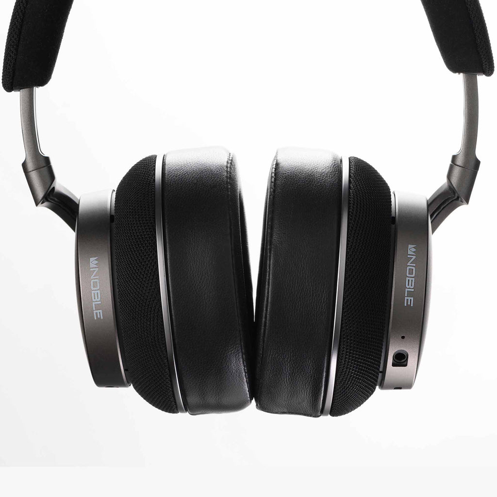 Close-up of black and silver Noble Audio FoKus Apollo Wireless Headphones with padded ear cups on white background