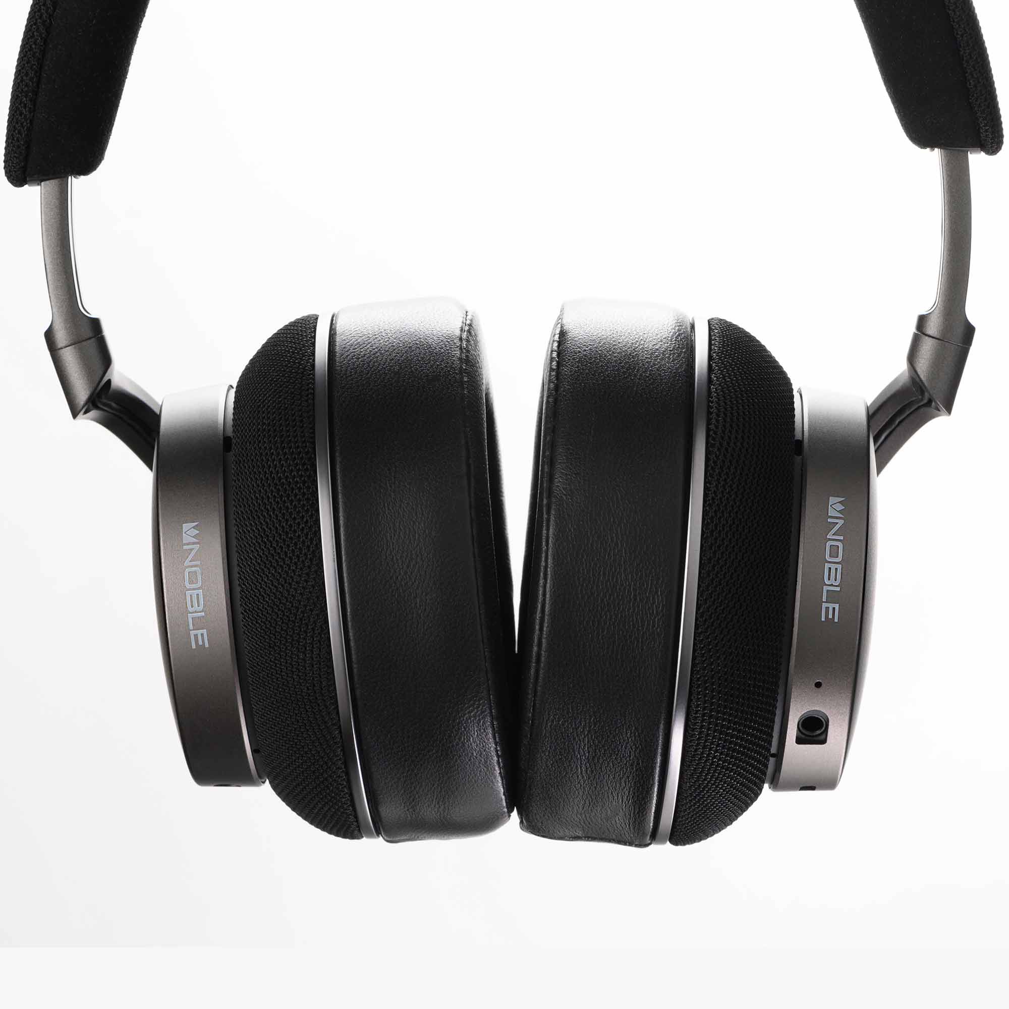 Close-up of black and silver Noble Audio FoKus Apollo Wireless Headphones with padded ear cups on white background