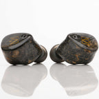 Noble Audio FoKus Prestige Wireless IEM with dark wood grain finish and gold logo on a reflective surface