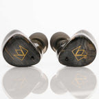 Noble Audio FoKus Prestige Wireless IEMs with dark wood finish and gold logo accents on reflective surface