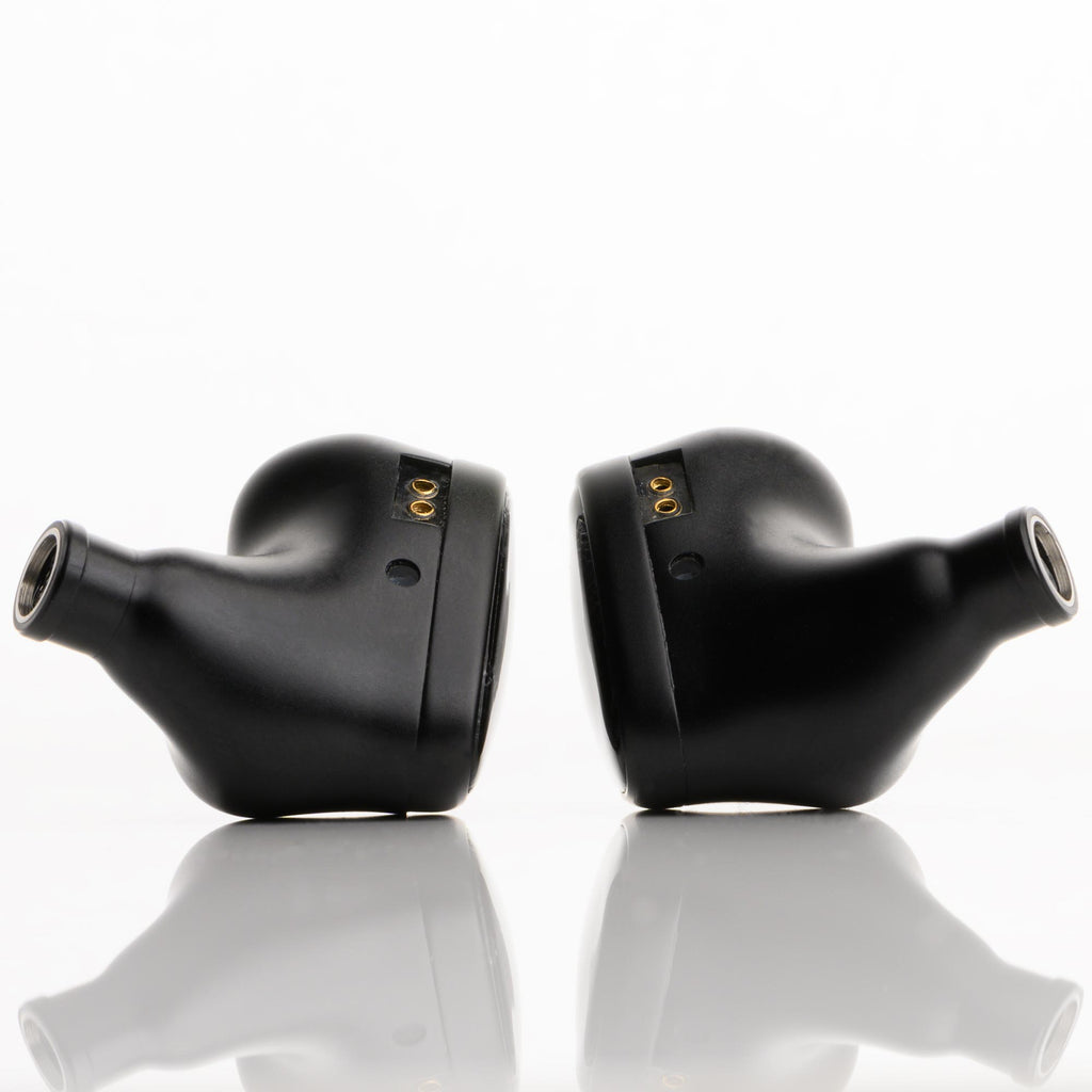 Pair of black Noble Audio Onyx Universal Fit In-Ear Monitors shown from side on reflective white surface