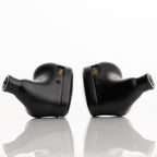 Pair of black Noble Audio Onyx Universal Fit In-Ear Monitors shown from side on reflective white surface