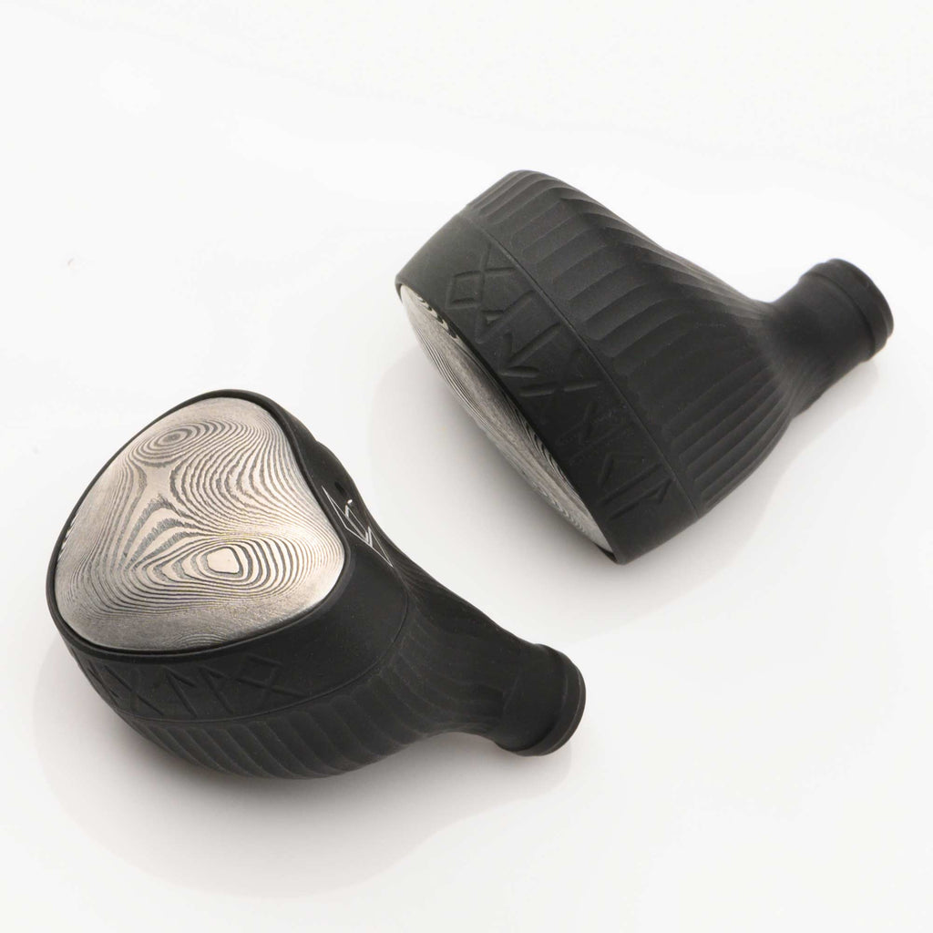 Pair of Noble Audio Viking Ragnar Universal-Fit IEM with textured black housings and patterned silver faceplates on white background
