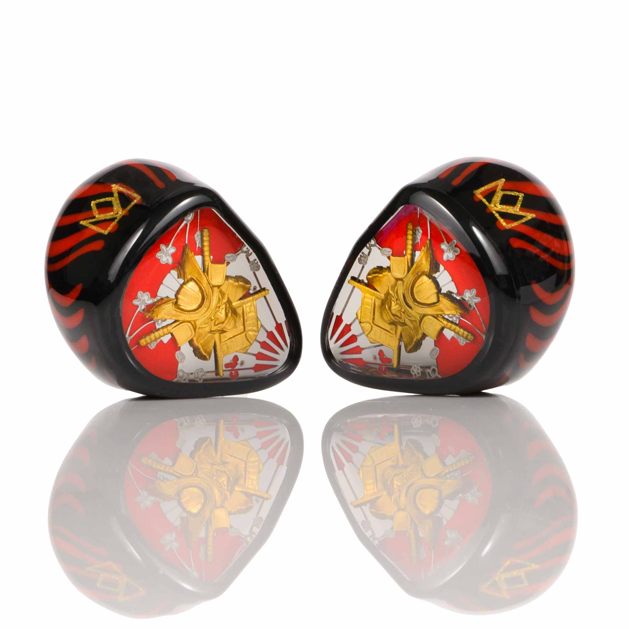 Noble Audio Shogun IEMs in black with red and gold samurai-inspired design reflecting on white surface