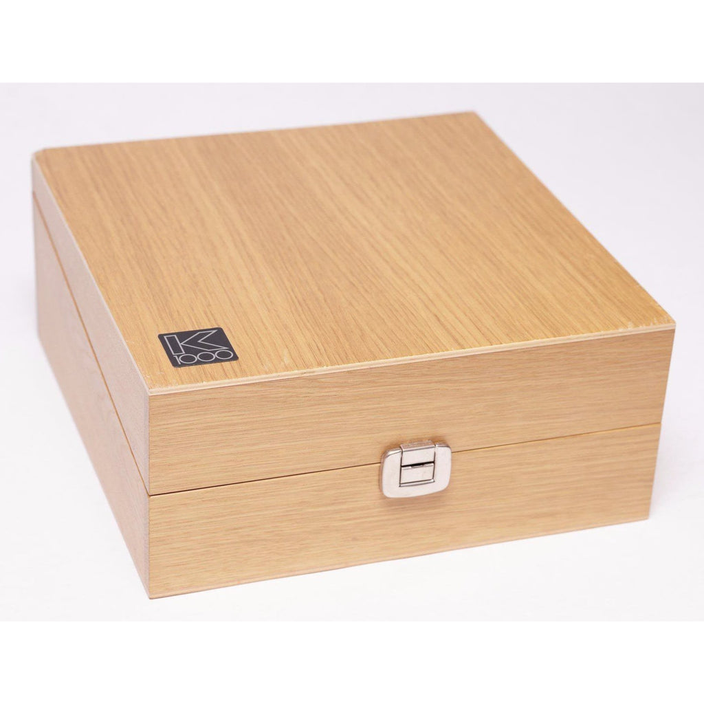Closed light wood storage box with a metal clasp and AKG K1000 logo on the top left corner on white background