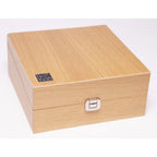 Closed light wood storage box with a metal clasp and AKG K1000 logo on the top left corner on white background