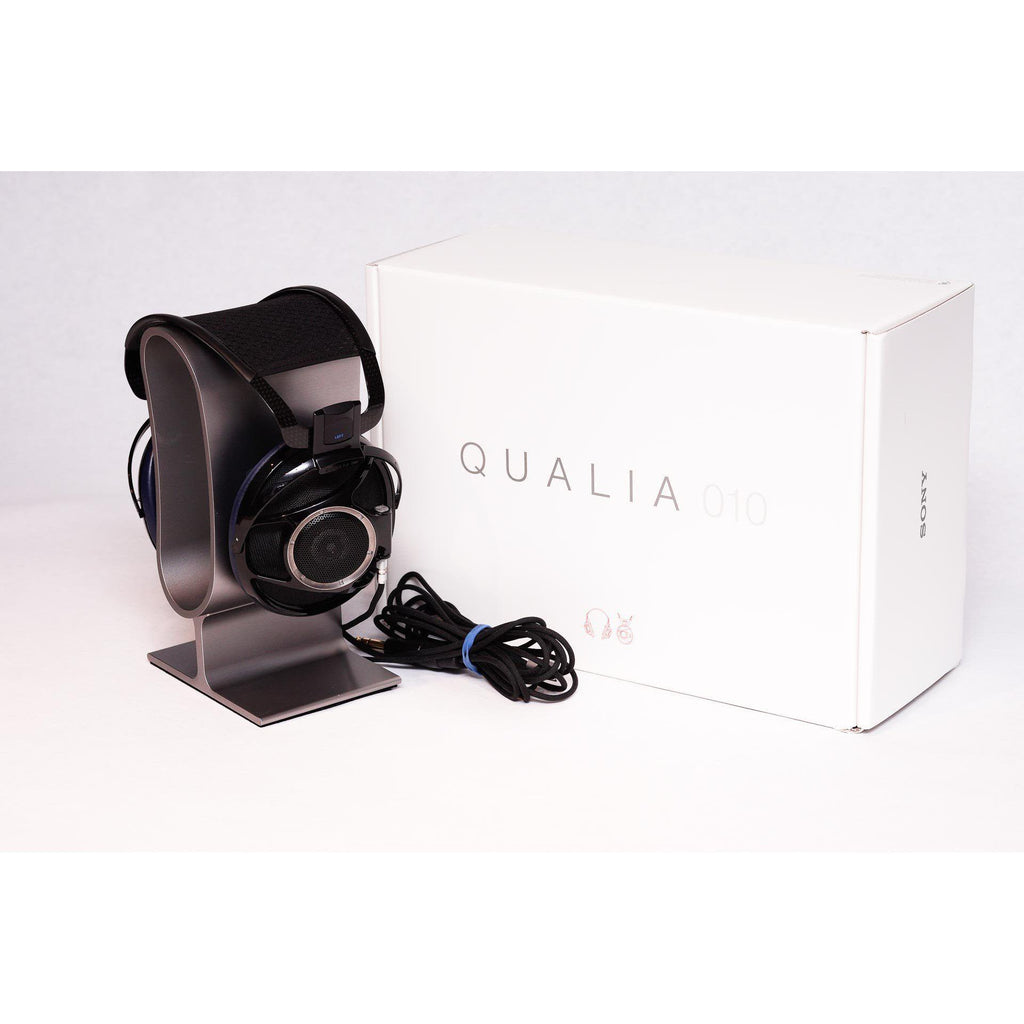 Sony Qualia 010 Reference Headphone with black and blue design on metal stand next to white product box on white surface