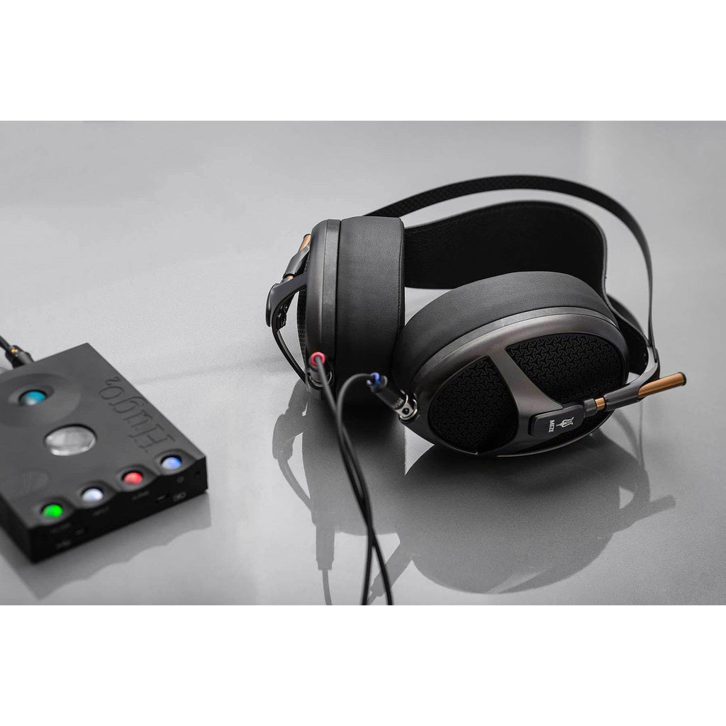Meze Empyrean open-back planar magnetic headphones connected to a black audio amplifier on a gray surface