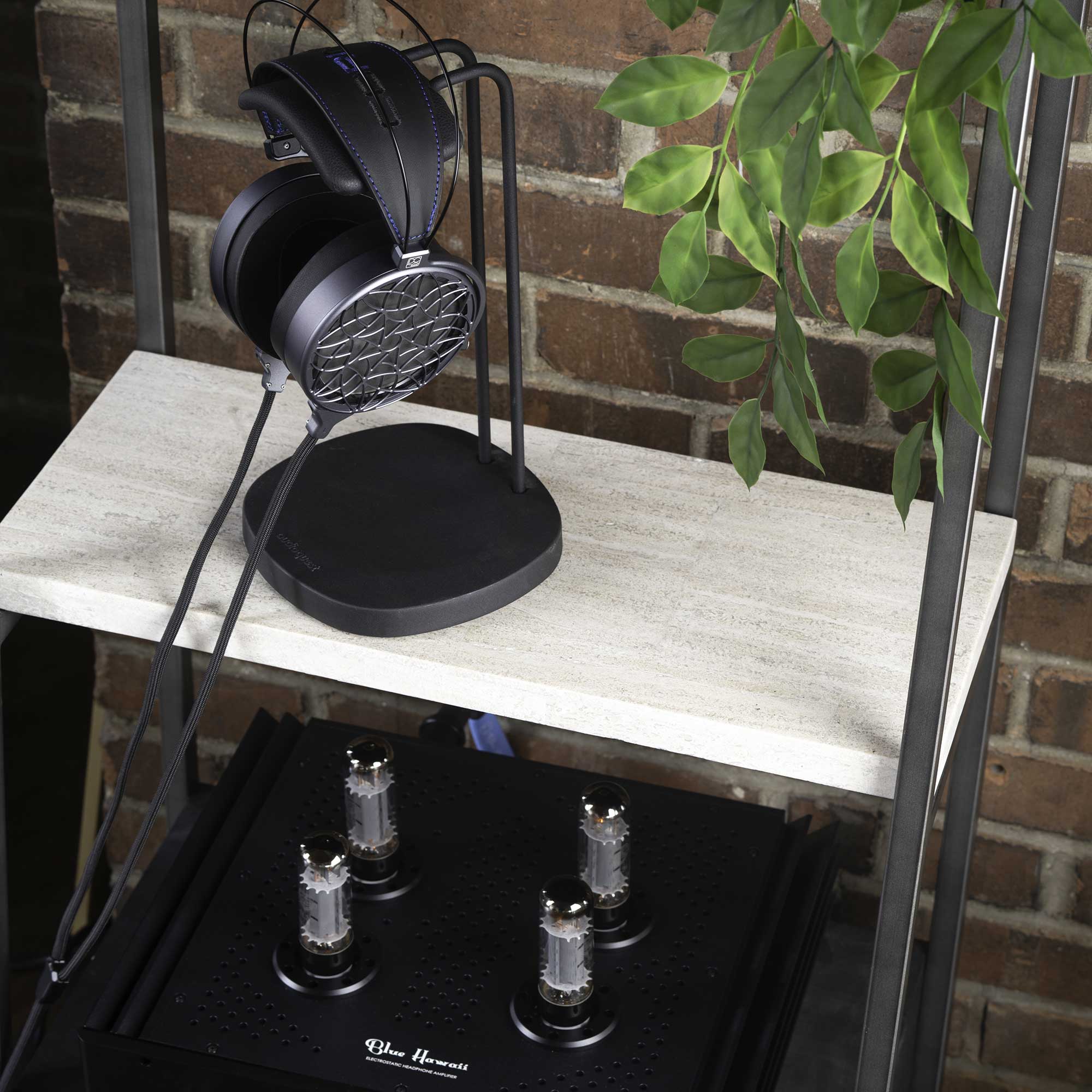 Dan Clark Audio Corina Reference Electrostatic Headphone resting on stand above a black amplifier with vacuum tubes on shelf