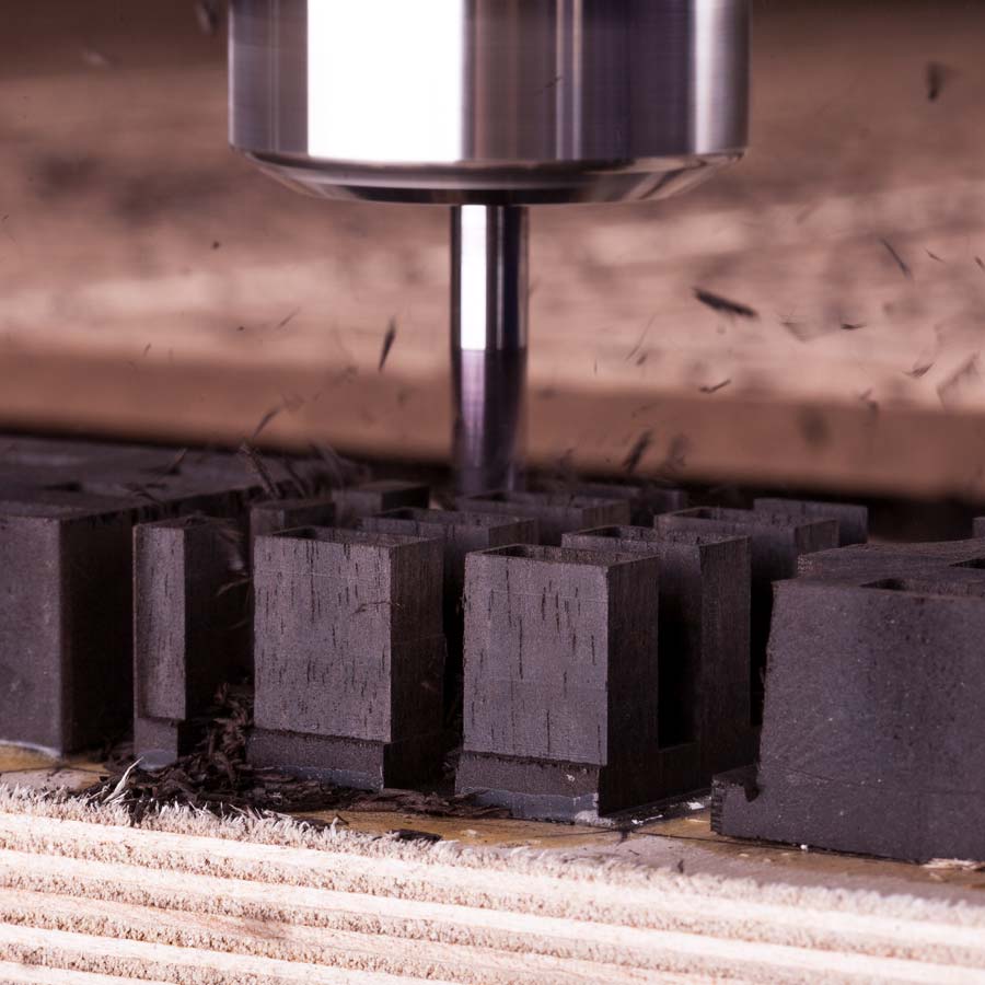Close-up of cutting tool shaping black material blocks during production of Kimber Kable Axios Copper Headphone Cable components