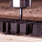 Close-up of cutting tool shaping black material blocks during production of Kimber Kable Axios Copper Headphone Cable components